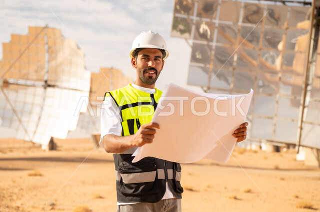 مهندس عربي يحمل مخططاً في محطة طاقة شمسية