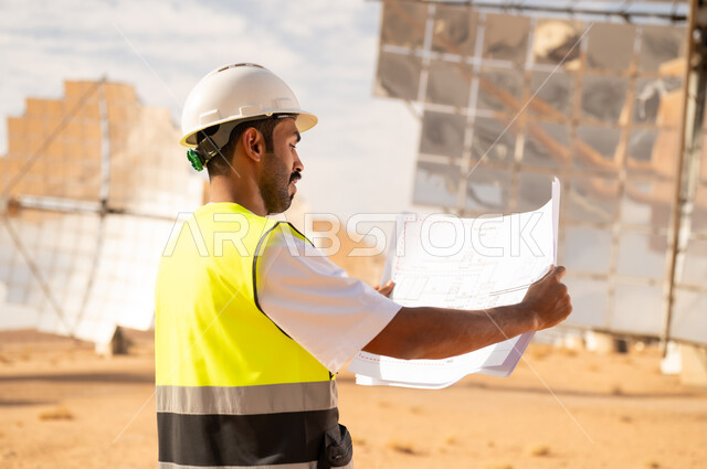 مهندس عربي في محطة طاقة شمسية يحمل مخططات