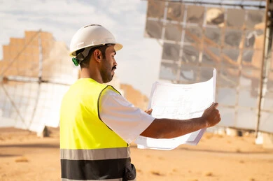 Arab Engineer at Solar Power Plant with Blueprints