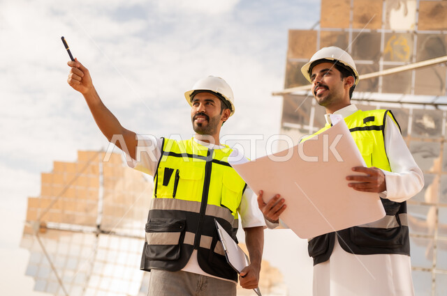مهندسون سعوديون في موقع بناء مع مخططات هندسية
