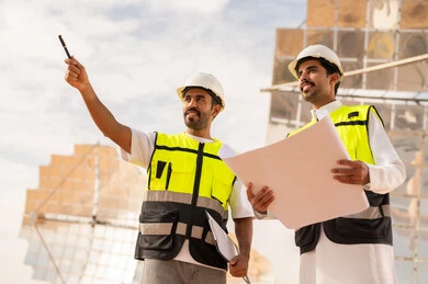 مهندسون سعوديون في موقع بناء مع مخططات هندسية