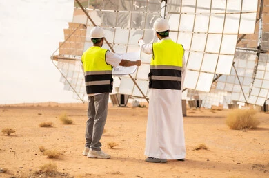 مهندسون في محطة طاقة شمسية صحراوية مع مخططات