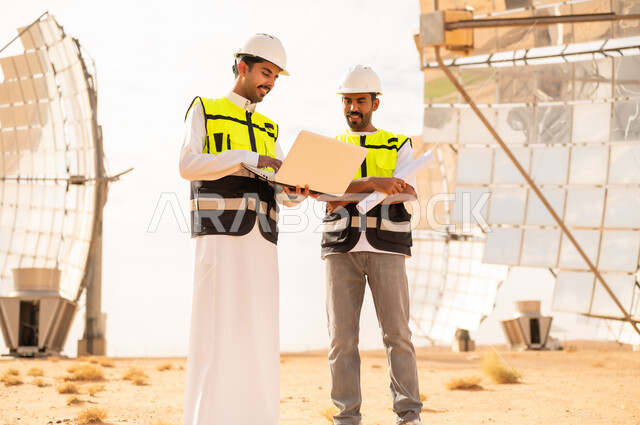 مهندسون عرب في محطة طاقة شمسية مع كمبيوتر محمول