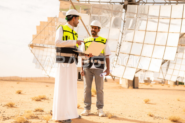 مهندسون سعوديون في محطة طاقة شمسية مع لابتوب