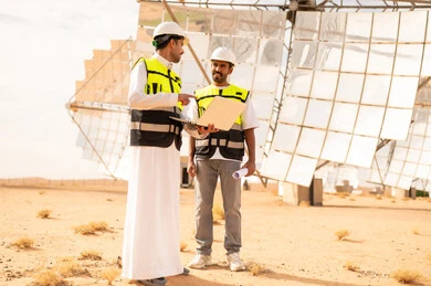 مهندسون سعوديون في محطة طاقة شمسية مع لابتوب