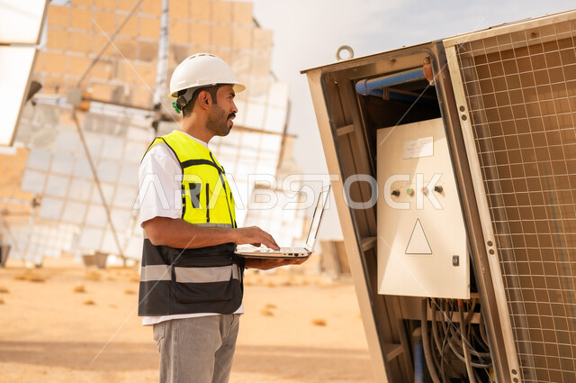 مهندس سعودي يفحص محطة طاقة شمسية بجهاز محمول