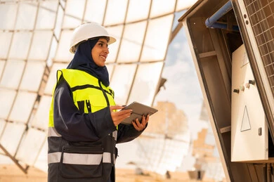 مهندسة سعودية في محطة طاقة شمسية مع جهاز لوحي