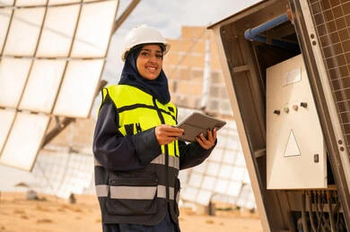 مهندسة عربية في محطة طاقة شمسية مع جهاز لوحي