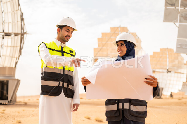 مهندسون سعوديون في محطة طاقة شمسية مع المخططات