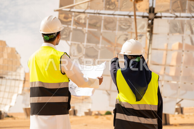 مهندسون سعوديون في محطة طاقة شمسية مع مخططات