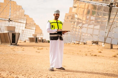 مهندس عماني في محطة طاقة شمسية مع لابتوب