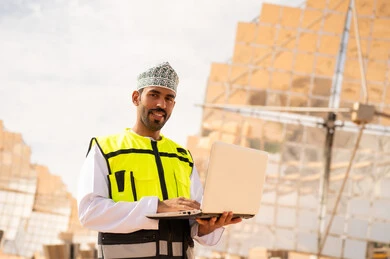 مهندس عماني في محطة طاقة شمسية مع لابتوب