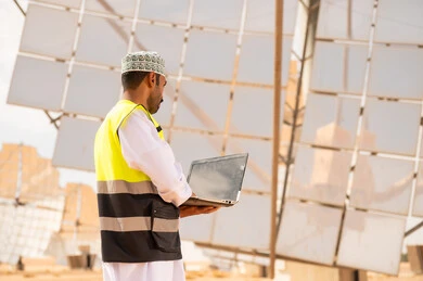 مهندس عماني في محطة طاقة شمسية مع كمبيوتر محمول