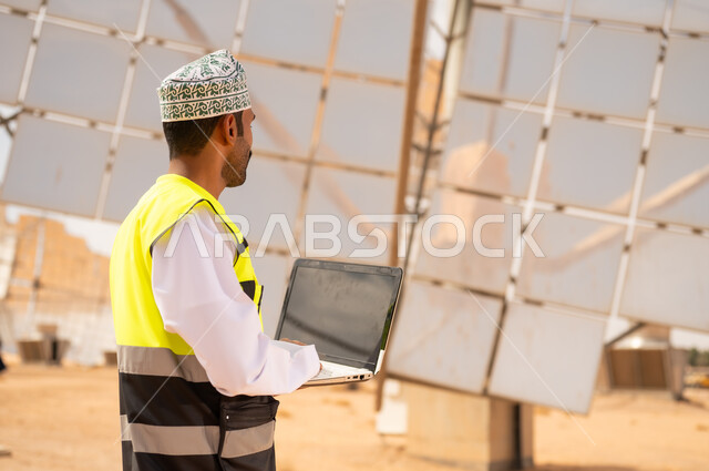مهندس عماني مع لابتوب في محطة طاقة شمسية