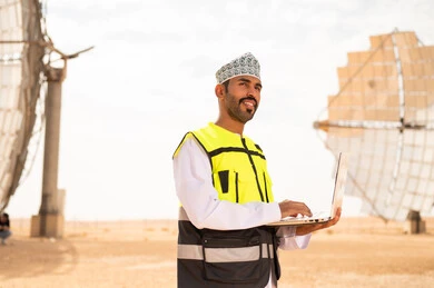 مهندس عماني في محطة طاقة شمسية مع لابتوب
