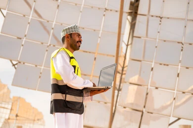 Omani Engineer with Laptop at Solar Power Plant