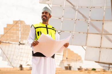 مهندس عماني في محطة طاقة شمسية مع مخططات