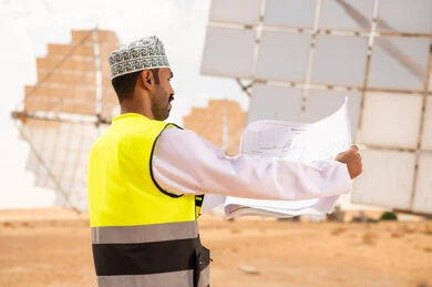 مهندس عماني مع مخططات في محطة طاقة شمسية