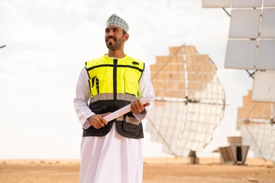 Omani Engineer at Solar Power Plant with Blueprints