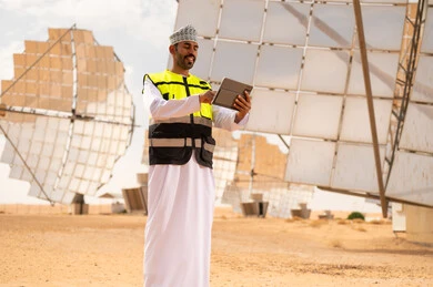 مهندس عماني مع جهاز لوحي في محطة طاقة شمسية