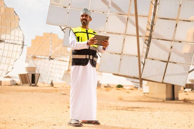 مهندس عماني في محطة طاقة شمسية مع جهاز لوحي