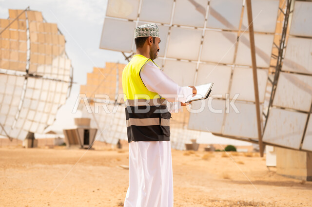 مهندس عماني يفحص ألواح الطاقة الشمسية في الصحراء