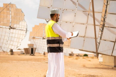 مهندس عماني يفحص ألواح الطاقة الشمسية في الصحراء