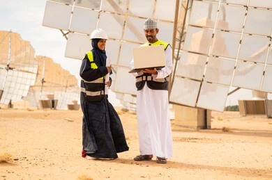 مهندسون عمانيون في محطة طاقة شمسية مع كمبيوتر