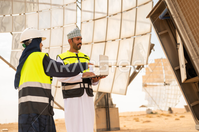 مهندسون عمانيون في محطة طاقة شمسية مع كمبيوتر