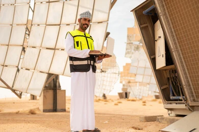 Omani Solar Energy Engineer Holding Laptop in Desert