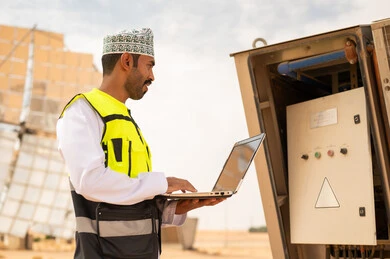 Omani Engineer Using Laptop at Solar Power Plant