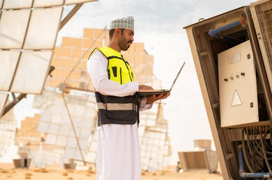 مهندس عماني في محطة طاقة شمسية مع كمبيوتر