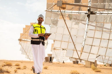 مهندس عماني مع جهاز لوحي في محطة طاقة شمسية