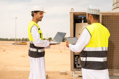 Omani Engineers Using Laptop at Industrial Site