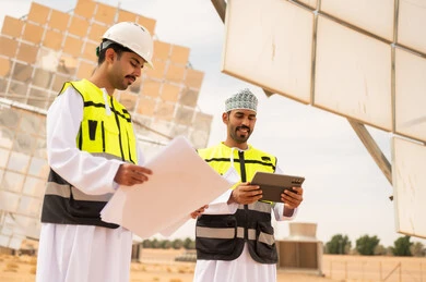 مهندسون عمانيون في محطة طاقة شمسية مع مخططات