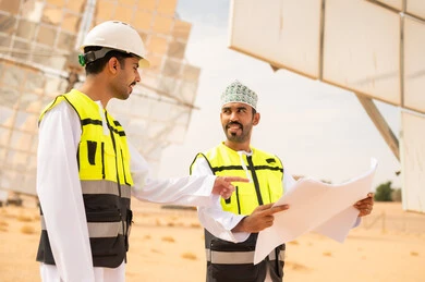 Omani Engineers at Solar Power Plant with Blueprints
