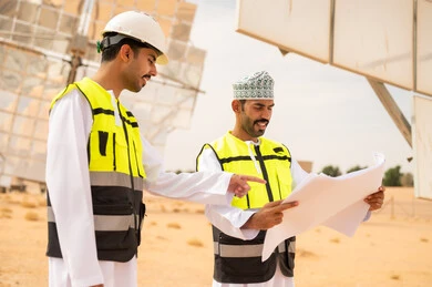 مهندسون عمانيون في محطة طاقة شمسية مع مخططات هندسية