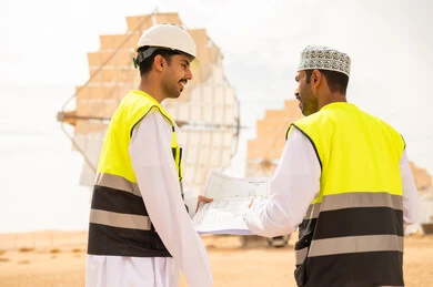 مهندسون عمانيون في محطة طاقة شمسية مع مخططات