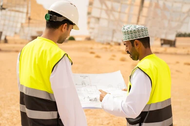Omani Engineers Reviewing Blueprint at Desert Site