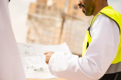 مهندس سعودي يراجع المخططات الهندسية في موقع بناء
