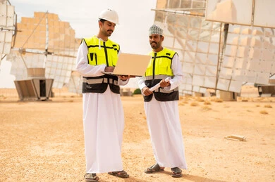مهندسون عمانيون في محطة طاقة شمسية مع كمبيوتر محمول