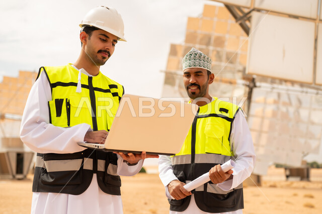 مهندسون عمانيون في محطة طاقة شمسية مع كمبيوتر محمول
