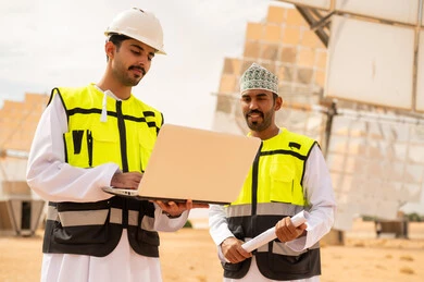 مهندسون عمانيون في محطة طاقة شمسية مع كمبيوتر محمول