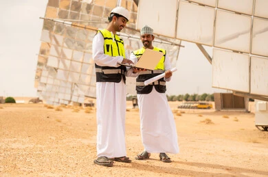 مهندسون عمانيون في محطة طاقة شمسية مع كمبيوتر