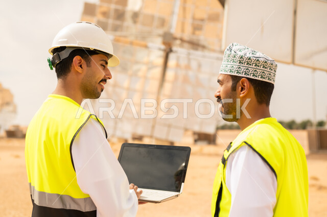 مهندسون عمانيون في محطة طاقة شمسية مع لابتوب