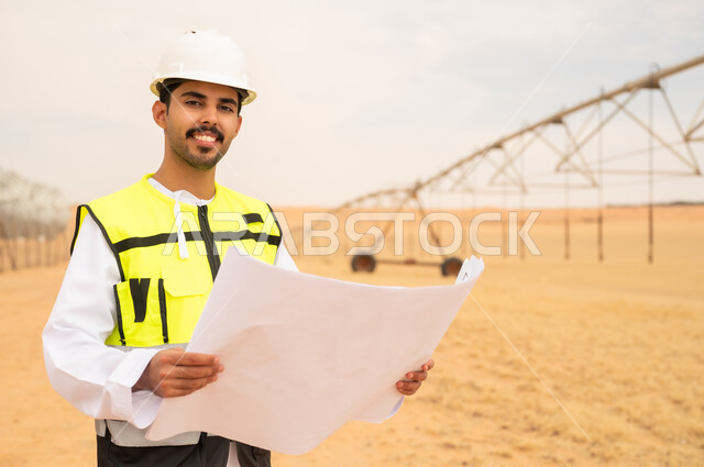 مهندس سعودي يحمل مخططاً في مزرعة صحراوية