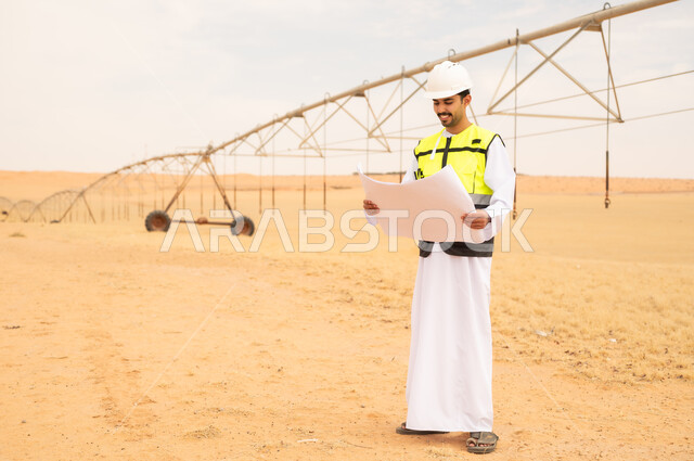 مهندس سعودي يحمل مخططاً في مزرعة ري صحراوية