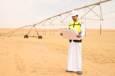 مهندس سعودي يحمل مخططاً في مزرعة ري صحراوية