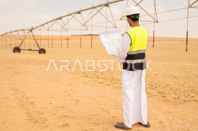 Saudi Engineer Holding Blueprint at Desert Irrigation Farm