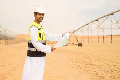 مهندس سعودي مع مخططات هندسية في موقع ري صحراوي